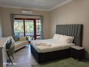 a bedroom with a bed and a couch and a window at Katberg Hotel & Mountain Resort in Karberg