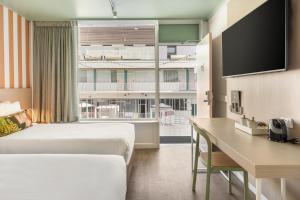a hotel room with two beds and a desk at Nightcap at the Cavenagh in Darwin