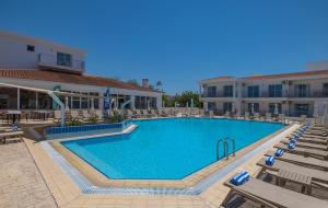 a swimming pool with chairs and a hotel at Greek Village - Latchi הכפר היווני - כשר in Polis Chrysochous