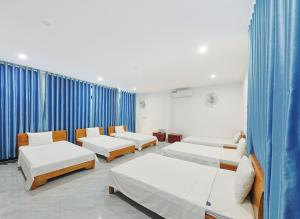 a hospital room with four beds and blue curtains at 359 Beach Hotel in Phú Xá