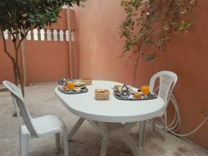 a white table with plates of food and two chairs at Relax House in Ikhorbane
