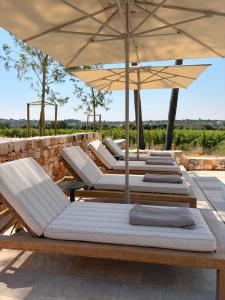 a row of lounge chairs and an umbrella at Tenuta Legaro in Cozzana