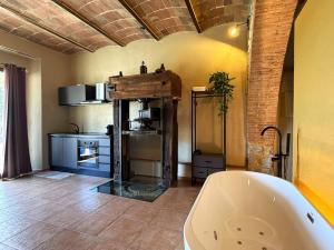 a bathroom with a bath tub and a kitchen at Domus Olea BnB in Roccatederighi