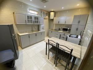 a kitchen with white cabinets and a wooden table and chairs at شقة راقية 3 غرف نوم وصالة ومطبخ وحمامين حي باقدو a1 in Medina +9 photos