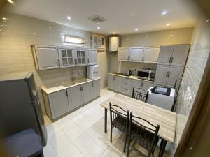 a large kitchen with a wooden table and chairs at شقة راقية 3 غرف نوم وصالة ومطبخ وحمامين حي باقدو a1 in Medina