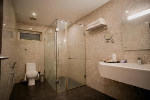 a bathroom with a shower and a toilet and a sink at Hotel New Indraprastha in Adūr +17 photos