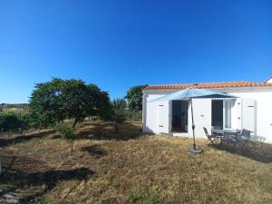 a white house with a table and a blue umbrella at Échappée iodée et nature à l'Île d'Oléron in Saint-Georges-dʼOléron