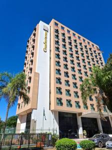 a hotel building with palm trees in front of it at Comfort Hotel Taguatinga, Metrô 600m, Sauna piscina academia e garagem Camas king e solteiro in Taguatinga