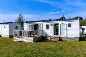 a white tiny house with a porch at Kustpark Nieuwpoort in Nieuwpoort