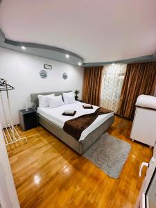 a bedroom with a large bed and wooden floors at Casa Maya in Douăzeci şi Trei August