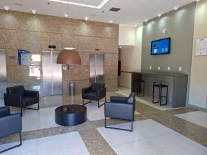 a waiting room with chairs and a tv on a wall at Comfort Hotel Taguatinga, Metrô 600m, Sauna piscina academia e garagem Camas king e solteiro in Taguatinga