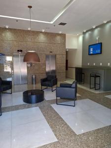 a lobby with chairs and a table and a tv at Comfort Hotel Taguatinga, Metrô 600m, Sauna piscina academia e garagem Camas king e solteiro in Taguatinga