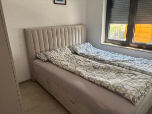 a bed with a comforter on it next to a window at Ferienwohnung Mina in Münsingen