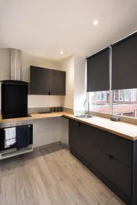 an empty kitchen with black cabinets and a sink at Stylish Flat in Peterborough Centre in Peterborough