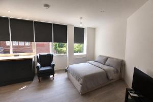 a bedroom with a bed and a desk and a chair at Stylish Flat in Peterborough Centre in Peterborough