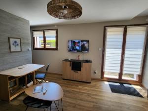 a room with a table and a desk and a tv at la perle du pibeste in Agos-Vidalos
