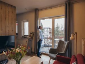a man looking out the window of a living room at Apartment Hainich in Mühlhausen