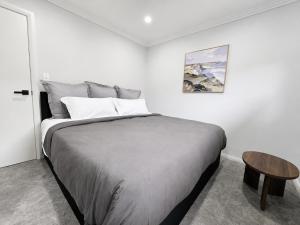 a white bedroom with a large bed and a table at Matildas Urban Escape 6-Min Station & Shops in Campbelltown South +6 photos