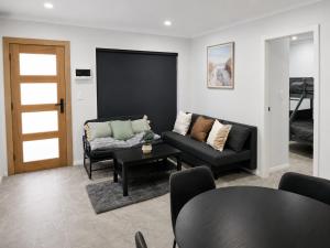 a living room with a couch and a table at Matildas Urban Escape 6-Min Station & Shops in Campbelltown South