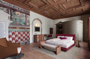 a bedroom with a bed and a table in it at Langenmantel Historic Suites in Termeno