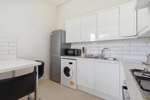 a white kitchen with a washing machine and a sink at Madeley Oak in Ealing