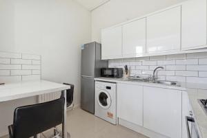 a kitchen with a sink and a washing machine at Madeley Oak in Ealing