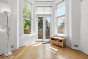 an empty living room with windows and a table at Madeley Oak in Ealing