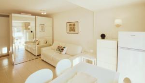 a white living room with a couch and a refrigerator at Le Studio des Deux Frontières in Beausoleil +2 photos
