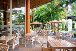 a restaurant with tables and chairs and palm trees at Andaman Pool Villas, Maikhao Beach Phuket in Mai Khao Beach
