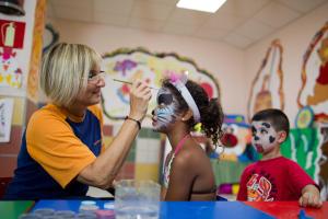 a woman painting a little girl with her face paint at Mirador Maspalomas by Dunas in Maspalomas