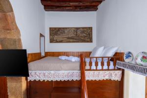 a small bedroom with a bed and a tv at IOANNAS ARCH HOUSE a in Gennadi