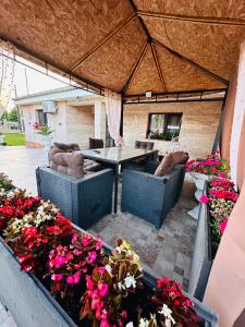 a patio with a table and chairs and flowers at Casa Maya in Douăzeci şi Trei August