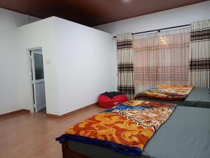 a bedroom with two beds and a window with curtains at Siriliya Homestay - Foreign Tourists Only in Nuwara Eliya