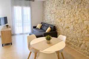 a living room with a table and a stone wall at Apartaments l'Escala Centre in L'Escala