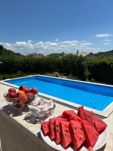 a table with bowls of watermelon and fruit next to a swimming pool at Casa Cavi Istria in Oprtalj +43 photos