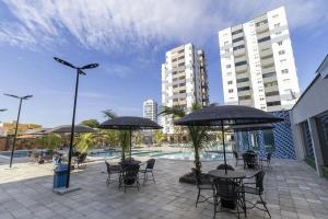 a patio with tables and chairs with umbrellas and a pool at CRCN - Aquarius Flat in Caldas Novas