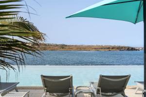 two chairs and an umbrella next to a body of water at Barceló Praia Cape Verde in Praia