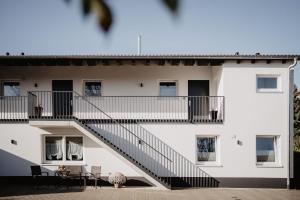 a white building with stairs and a table and chairs at Rheinwald in Weisweil