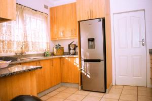 a refrigerator in a kitchen with wooden cabinets at The Cottage in Lilongwe