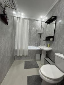 a white bathroom with a toilet and a sink at Жастар in Astana