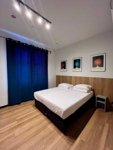 a bedroom with a large white bed with blue curtains at MoHo XL in Wrocław