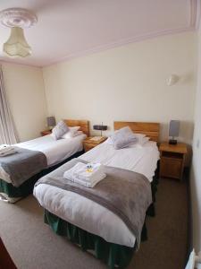 ein Hotelzimmer mit zwei Betten und zwei Tischen in der Unterkunft Glendower Hotel in Goodwick + 8 Fotos