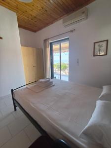 a large bed in a room with a large window at Paradisos in Loutsa