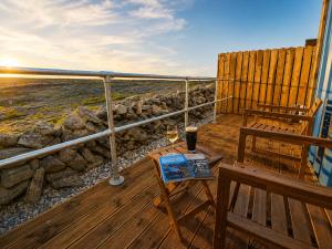 a balcony with a bench and a table with a glass of wine at Aran Islands Hotel in Kilronan