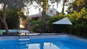 a swimming pool with an umbrella and a house at B&B A Casa Di Gina in Polignano a Mare