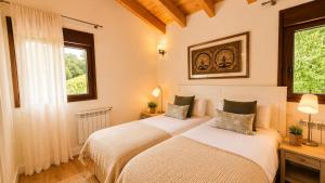 two beds in a room with two windows at La Cuadra de San Pedro Ribadesella in Ribadesella