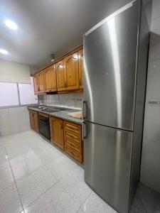 a stainless steel refrigerator in a kitchen with wooden cabinets at Apartamento CASA EL MORABITO in Puente Genil