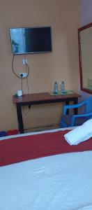 a bedroom with two beds and a desk with a tv at Royal pine cottage hotel in Ruiru