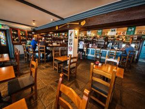 a restaurant with wooden tables and chairs and a bar at Aran Islands Hotel in Kilronan