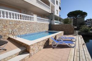 a swimming pool with two chairs next to a building at Teresita 2 in Empuriabrava